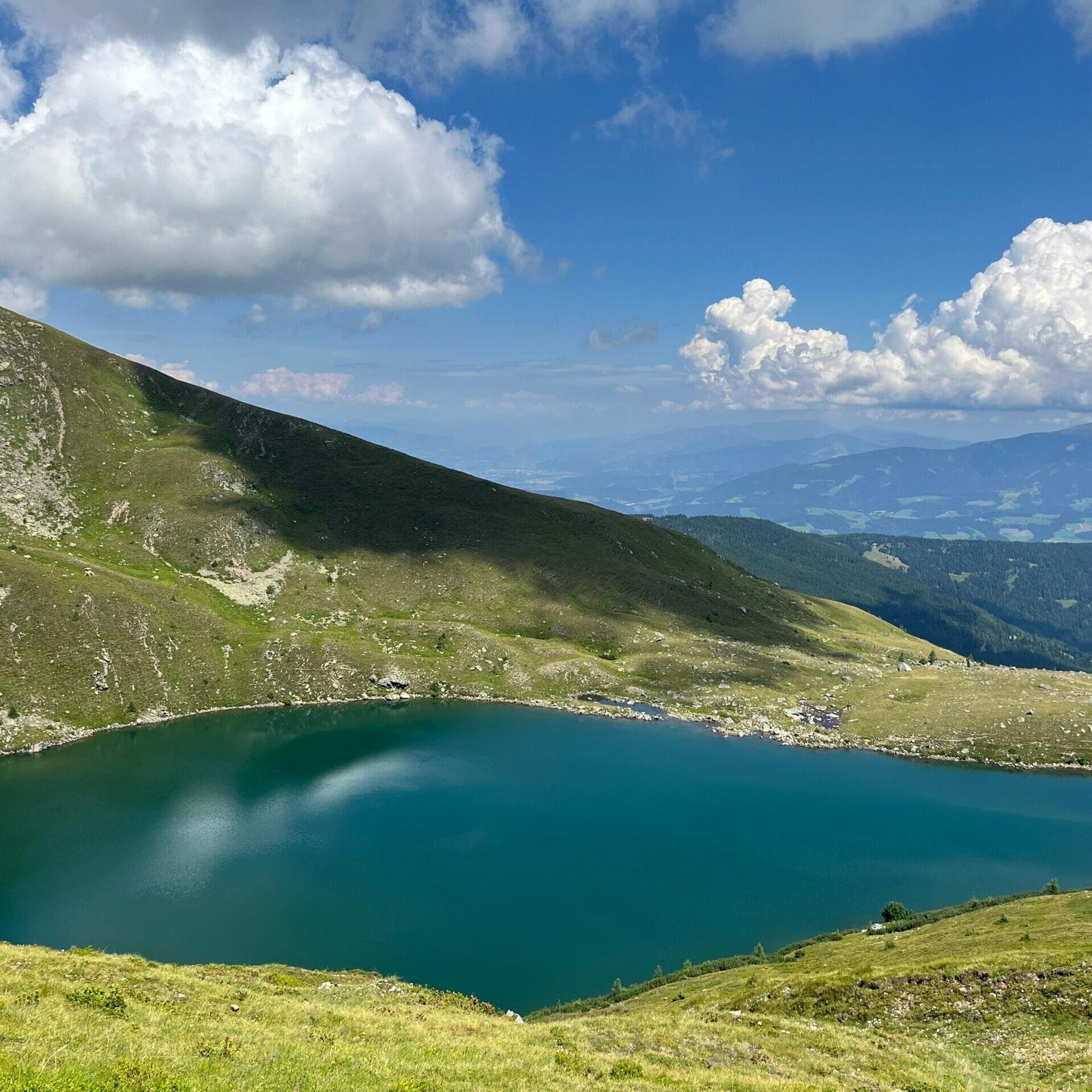 A breathtaking view of an alpine lake surrounded by lush mountains in Styria, Austria.