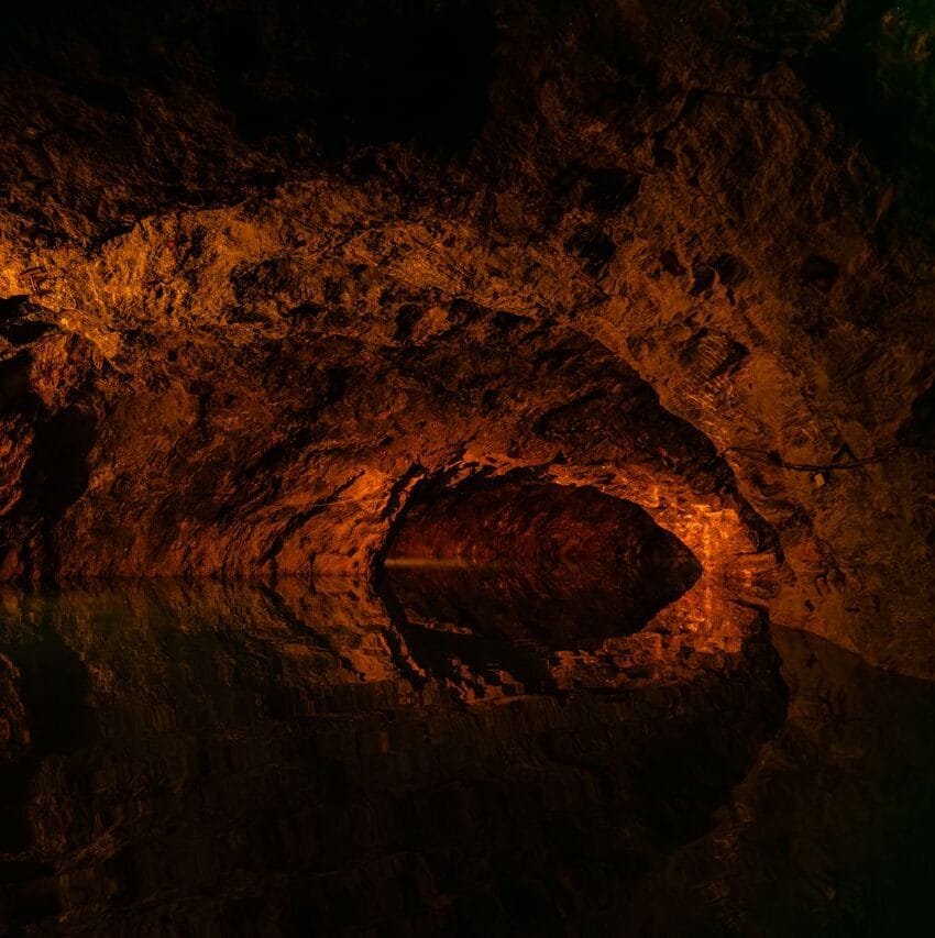 Explore a dimly lit cave in Austria with stunning water reflections.